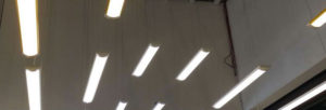 Plusieurs réglettes LED lumineuses suspendues au plafond d'un espace industriel